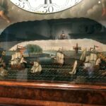 Onderdeel van een klok met daarop afgebeeld de scheepvaart in Amsterdam.