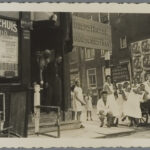 Een groot bord 'Judenstrasse' aan het begin van de Nieuwe Kerkstraat in 1941. Verplegend personeel van het Ned. Isr. Ziekenhuis op de voorgrond. Achter de 2 linkermeisjes een deel van het huidige nr. 2A. Collectie Joods Museum