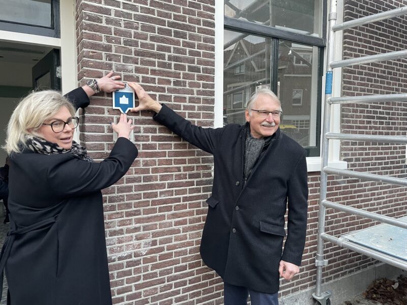 Wethouder Stam en oud adjunct-directeur van Stadsherstel Hulscher bevestigen het schildje van Stadsherstel Amsterdam