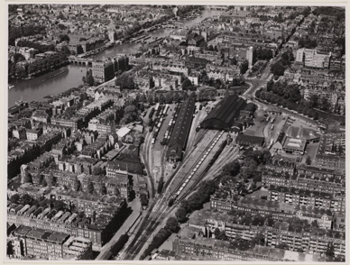 1930 ca. luchtfoto van het Weesperpoortstation. Het kopstation ligt tot najaar 1939 aan de Spoorbaanstraat (nu Wibautstraat), en is het vertrekpunt van de trein naar Utrecht en van de Gooische Stoomtram.